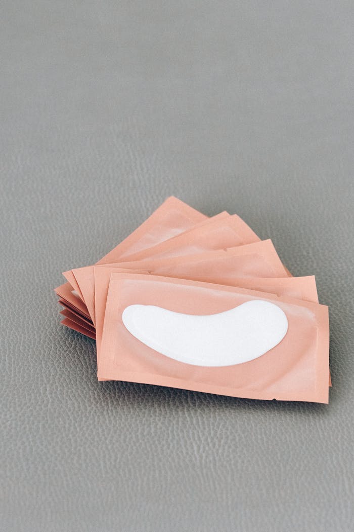 Close-up of brown packets containing white eye patches on a textured gray surface.